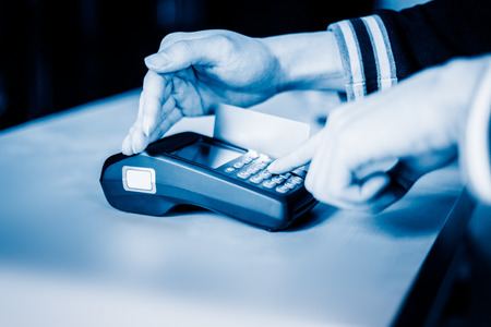 Male enters PIN code on wireless POS machine with hand coveringの写真素材