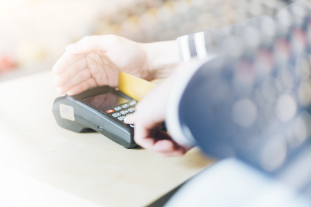 Male enters PIN code on wireless POS machine with hand covering