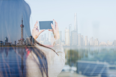 woman taking photo of the bund with smartphone,shanghai,chinaの写真素材