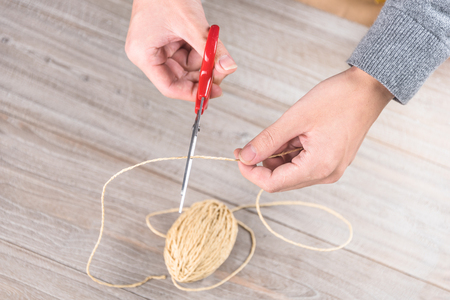 close-up of man cutting brown cord to wrapping the christmas present.の写真素材
