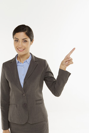 Businesswoman pointing to the left, smilingの写真素材