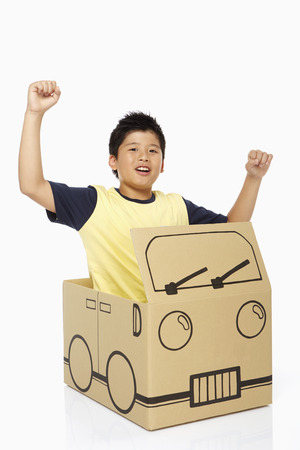 Boy sitting in a cardboard bus, cheeringの写真素材