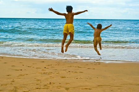 two children jumping on the beach の写真素材