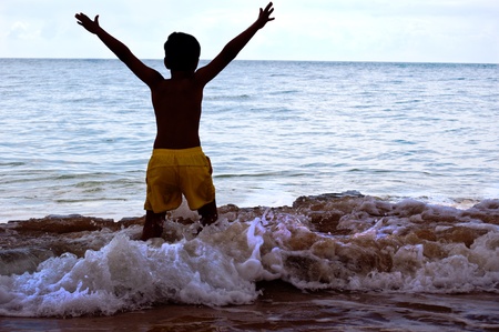 child jumping on beach with blue sky in the backgroundの写真素材