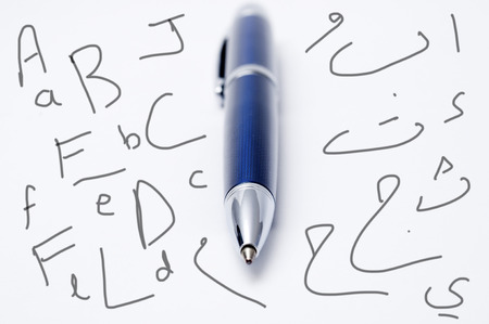 Closeup of a pen lying on a background with Ingls and arabic letters