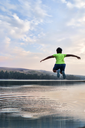 Happy child jumping on the lakeの写真素材