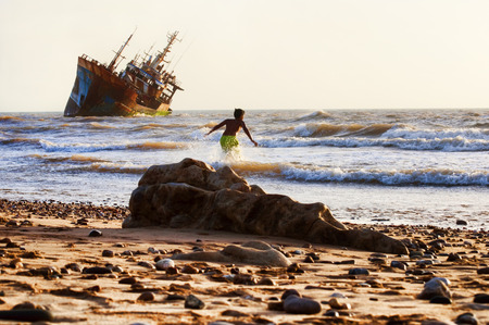 ship-wreck in  la playa beach with child playing on beach, western sahara.の写真素材