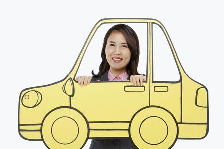 Businesswoman standing behind a cardboard carの写真素材