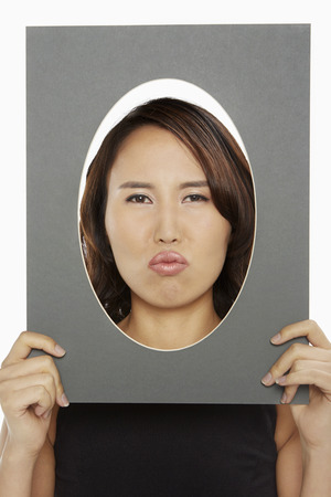 Woman holding up an oval frameの写真素材