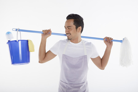 Man carrying mop and bucket on his backの写真素材