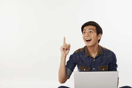 Man holding up index finger while using laptopの写真素材