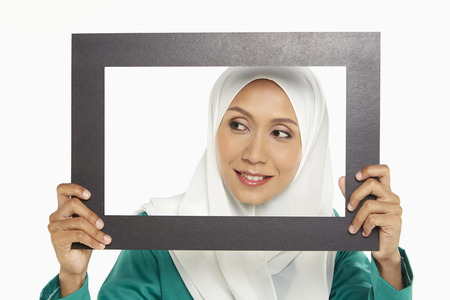 Woman looking through a cut out frameの写真素材