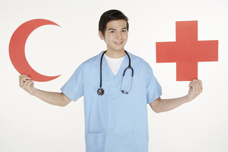 Medical personnel holding up a cut out red crescent and cross signのeditorial素材