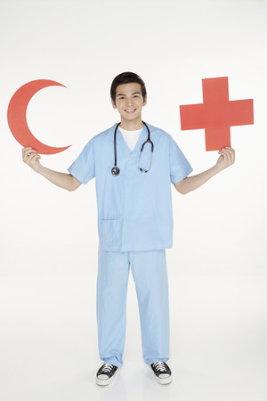 Medical personnel holding up a cut out red crescent and cross signのeditorial素材