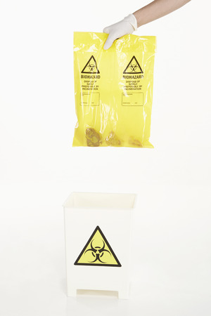 Human hands disposing biohazard wasteの写真素材