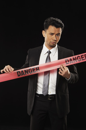 Businessman standing behind a 'Danger' tapeの写真素材