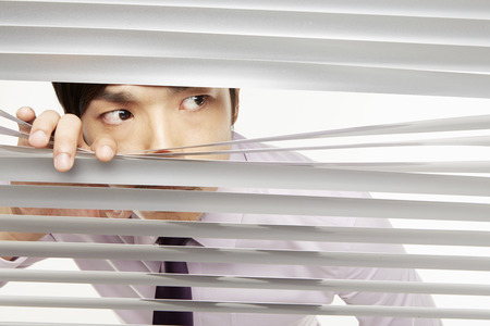 Businessman peeking through window blindsの写真素材