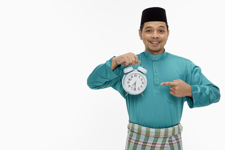 Man in traditional clothing holding up a clockの写真素材