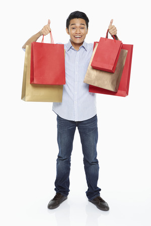 Man carrying shopping bags and showing hand gestureの写真素材