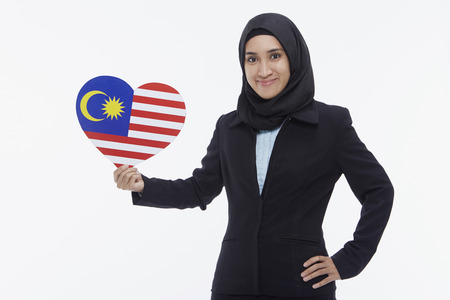 Businesswoman holding up a heart shaped Malaysian flagの写真素材