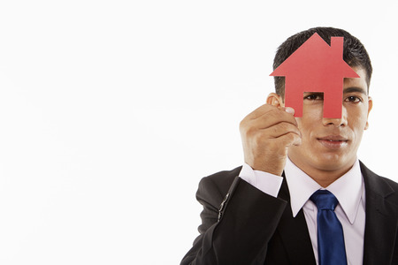 Businessman looking through a cut out houseの写真素材