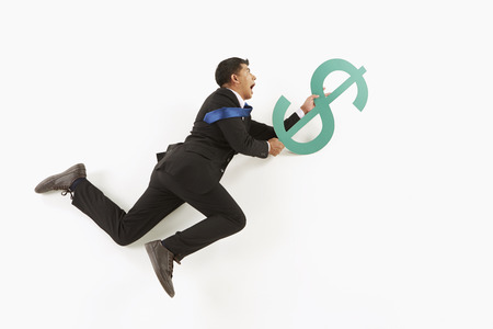 Businessman hanging on to a dollar signの写真素材
