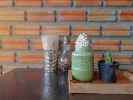 selective focus of Place a glass of green tea on a wooden tray that is placed on a wooden table with dark brownの写真素材