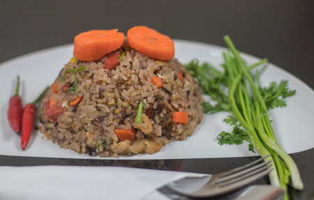 on selective soft focus of Fried rice with herbs. In a circular plate in black and white. Placed on a wooden table made with rice, fried rice Wright Berry and several types of herbs.の写真素材