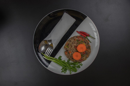 Fried rice with herbs. In a circular plate in black and white. Placed on a black desk, fried rice Wright Berry and several types of herbs.の写真素材