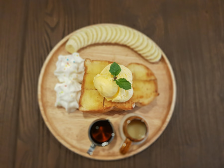 Sliced banana, sweetened honey, toasted bread in a wooden plate on the table.の写真素材