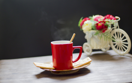 Hot coffee in red glass placed on a saucer with two bread plates. And placed on a wooden tableの写真素材