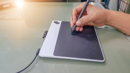 Middle-aged men are using the pen mouse   in the computer drawing.