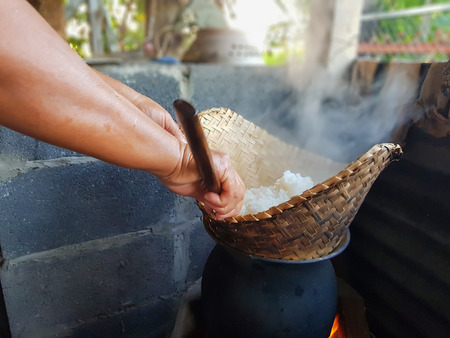 Middle aged women steamed rice By charcoal oven.の写真素材