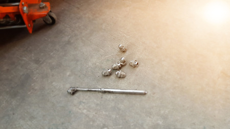 Car mechanic patching a tire. Nut screwing a car hub. Jack for lifting the vehicle.の写真素材