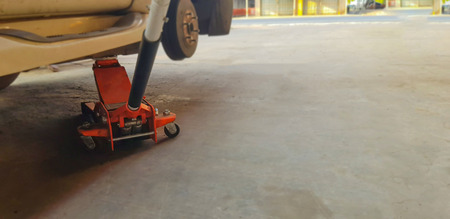 Car mechanic patching a tire. Nut screwing a car hub. Jack for lifting the vehicle.の写真素材