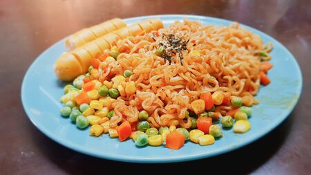 On selective focus of Stir fried noodles with cereal seeds and hot dogs on a green circular seram dishの写真素材