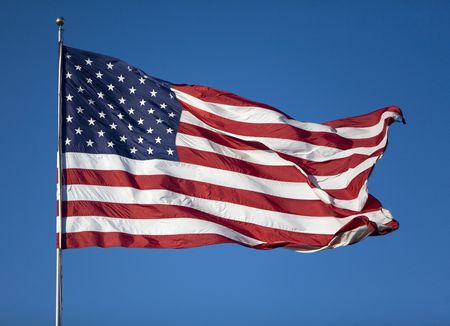 Very large United States Flag blowing in the wind on a cloudless day