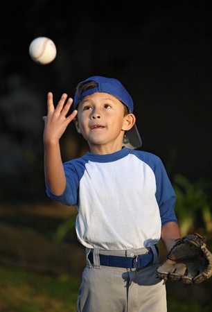 Happy smiling young latino boy dressed in blue baseball sleeves with cap, glove and ballの写真素材