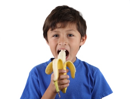 Young happy child eating fresh banana - on white backgroundの写真素材