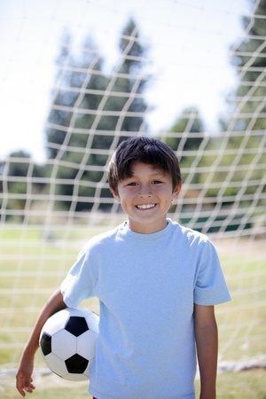 Backlit boy with Soccer ball with goal behind and blurred background providing copy space aboveの写真素材