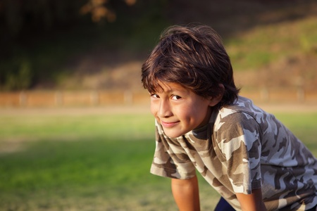 Happy smiling boy in the park near to sunset with shallow depth of field and copy space to leftの写真素材