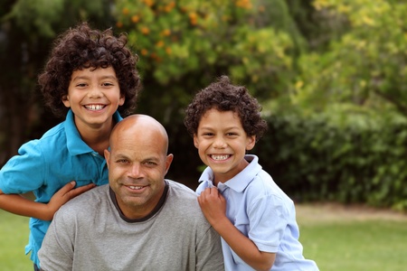 Mixed race father and sons playing outside