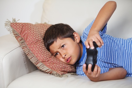 Young boy playing computer game while relxing on the sofaの写真素材