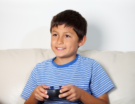 Young boy playing computer game while relxing on the sofa
