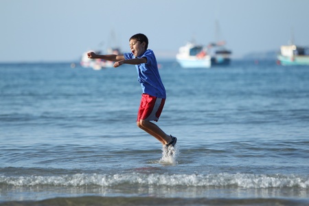 Young boy plays and runs in the surf along an English beach near sunsetの写真素材