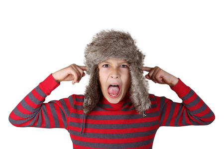 Boy in furry hat puloling funny faces on white background