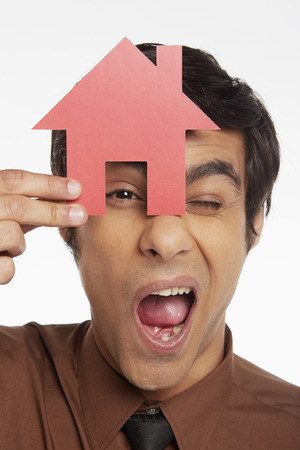 Businessman looking through a cut out houseの写真素材