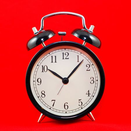 black alarm clock isolated on red background の写真素材