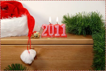 Happy New Year -2011 candles isolated on woden table,with tree branch and Santa hatの写真素材