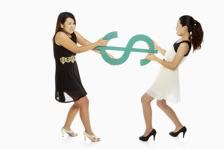 Two women pulling a dollar signの写真素材